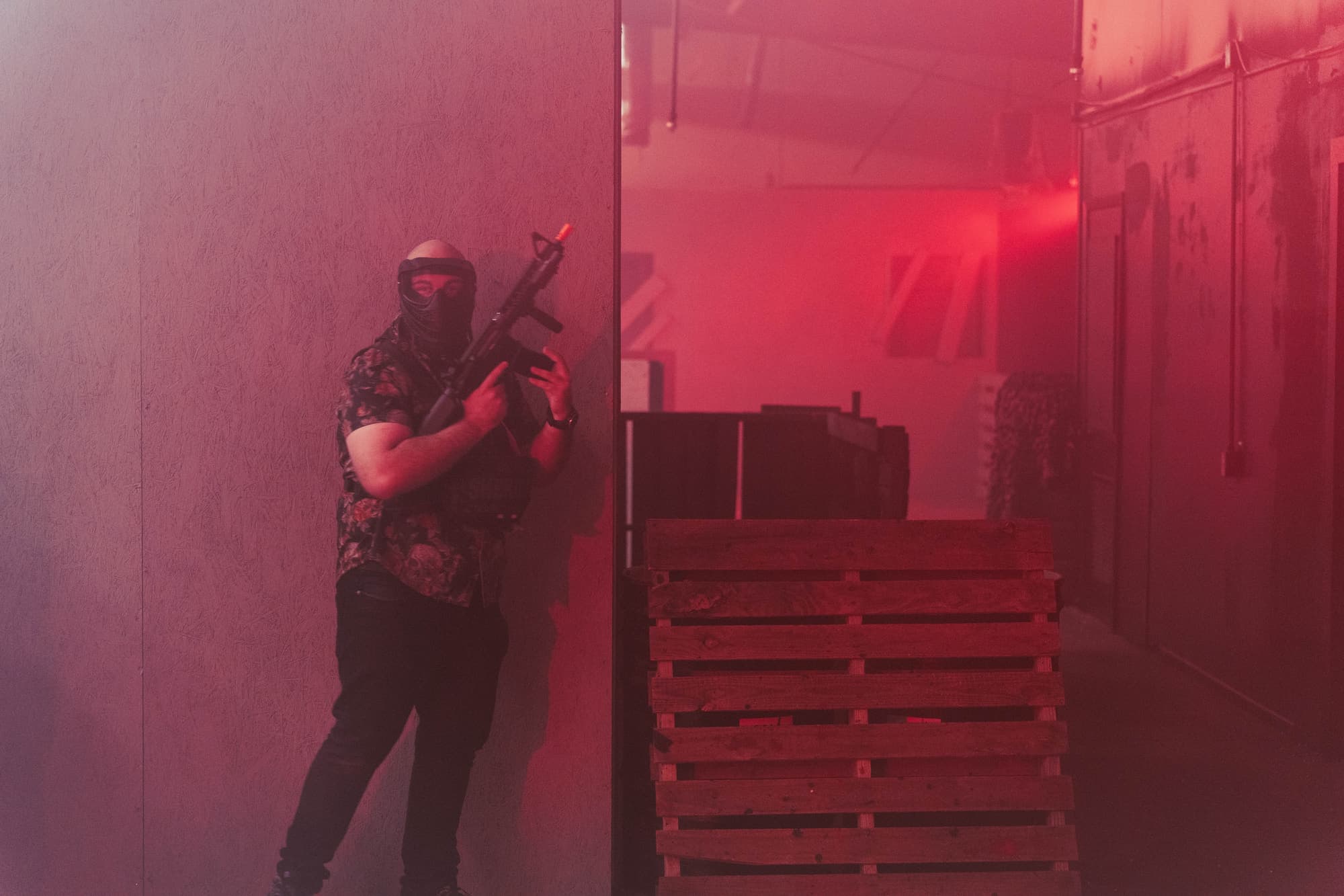 Player holding a corner next to stacked pallets in red light