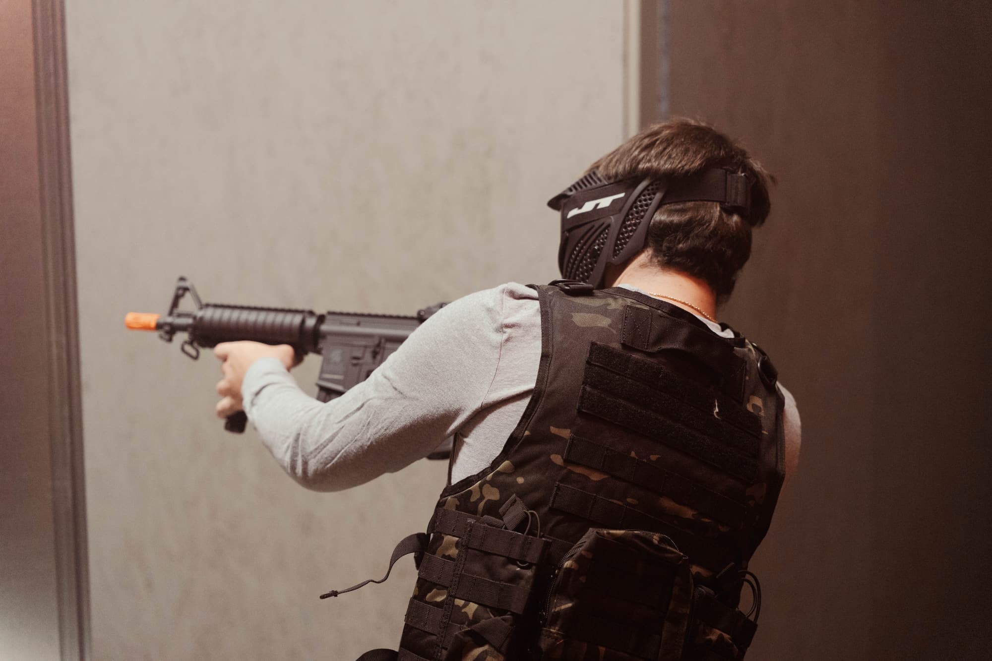 Player in a plate carrier aiming down a bright hallway