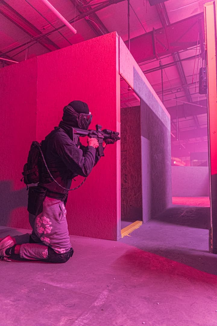 Masked player aiming from a doorway in red light