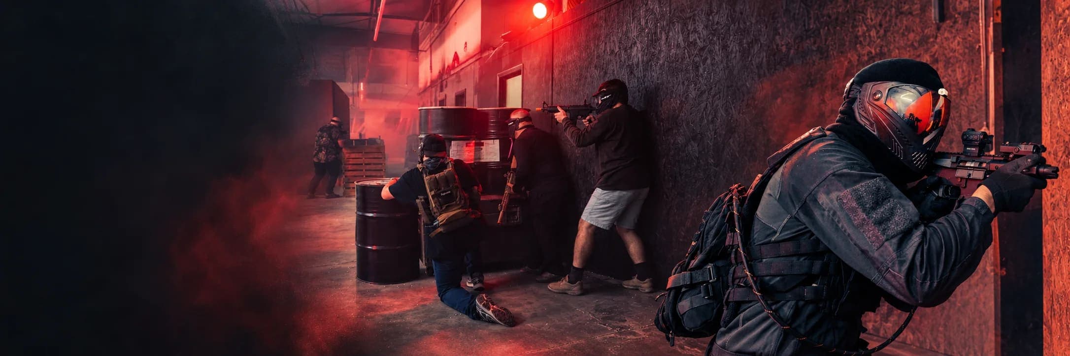 Squad of players holding positions along a red-lit arena wall, one in the foreground aiming past the corner