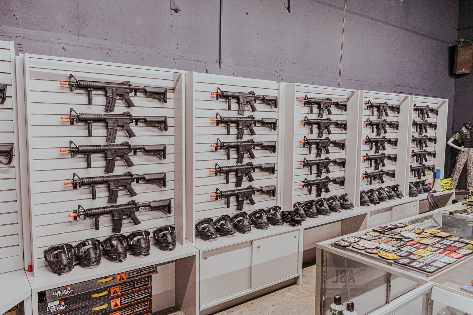 Rental wall with rows of airsoft replicas and masks